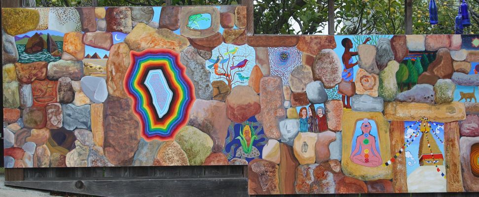 A long acrylic mural of a stone wall with holes revealing small birds, camels, people and cats, by Jenny Badger Sultan's family.