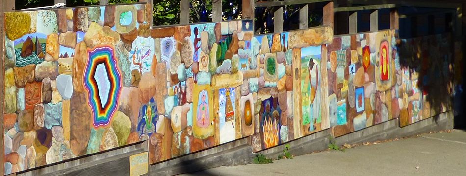 A long acrylic mural of a stone wall with holes revealing small birds, camels, people and cats, by Jenny Badger Sultan's family.